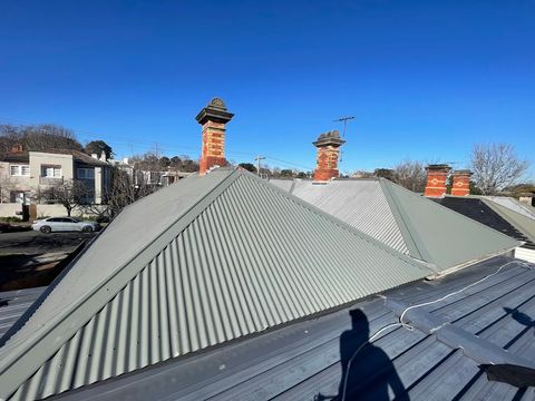 New corrugated roof on a period home with brick chimneys